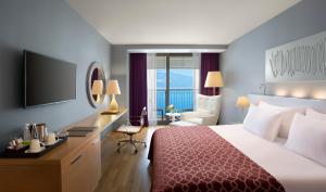 Habitación de hotel con cama, escritorio y TV. en Akra Hotel en Antalya
