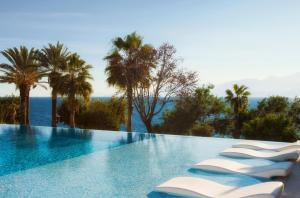 a swimming pool with a view of the ocean and palm trees at Akra Hotel in Antalya