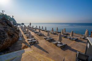 una fila de sillas y sombrillas en una playa en Akra Antalya, en Antalya