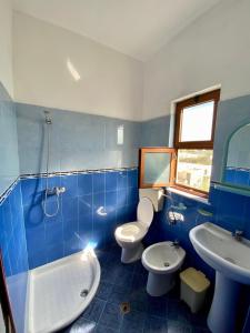 a blue and white bathroom with two toilets and a sink at Vila Rrodhe in Durrës