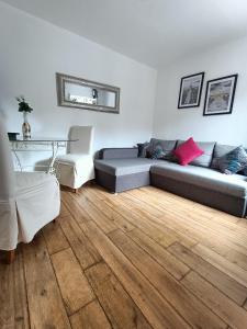 uma sala de estar com um sofá e um piso de madeira em Charmante Maisonnette indépendante avec parking 5 mn Rouen em Franqueville-Saint-Pierre