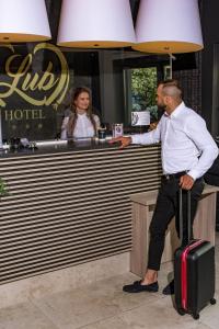 un uomo in piedi in un bar con una valigia di Studia LubHotel a Lublino