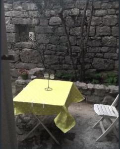 uma mesa amarela e uma cadeira em frente a uma parede de pedra em Les Faveyrolles à Labeaume em Labeaume