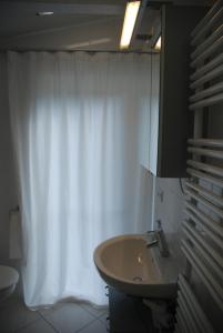 a bathroom with a sink and a white shower curtain at Das grüne Häusle in Osterholz-Scharmbeck