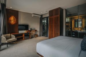 a bedroom with a bed and a desk and a television at The Ning Resort Ubud in Ubud