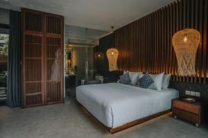 a bedroom with a large white bed and a bathroom at The Ning Resort Ubud in Ubud