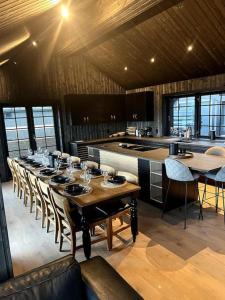 Cette chambre dispose d'une cuisine et d'une grande table avec des chaises. dans l'établissement Ny kvalitetshytte-158 m2-Kikut!, à Flatåker