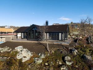 a house with a black roof and some rocks at Ny kvalitetshytte-158 m2-Kikut! in Flatåker