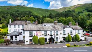 an old white house with a mountain in the background at The Swan at Grasmere- The Inn Collection Group in Grasmere