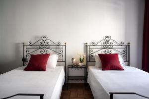 グッビオにあるHotel San Marcoのベッドルーム(赤い枕付きのベッド2台付)