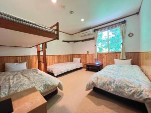 a bedroom with two beds and a window at Pension Alps Hakuba in Hakuba