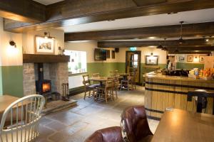 a restaurant with a fireplace and tables and chairs at Square & Compass in Two Dales