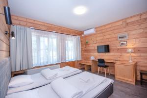 a bedroom with two beds and a desk and a television at Kurgo Villa self check-in hotel in Pärnu