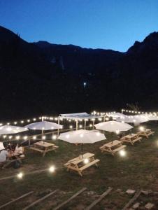 un groupe de tables avec parapluies dans un champ la nuit dans l'établissement Albergue de Arrojo, à Bárzana