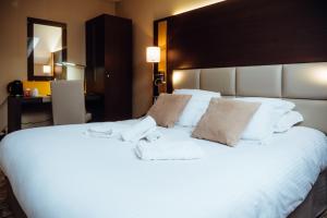 a large white bed with two towels on it at Hotel Le Dauphin in Honfleur