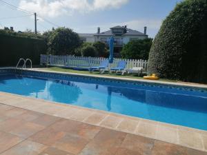 a swimming pool with two chairs and a white fence at Apartamento Pueblo De Mogro in Mogro