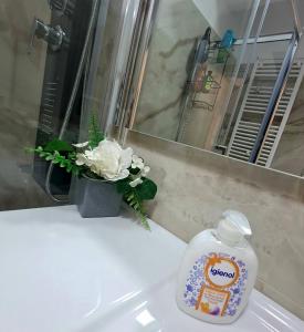 a bottle of soap on a bathroom sink with a vase of flowers at Imperium Residence in Sfîntu Ilie