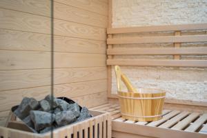 een sauna met een container van rotsen en een houten emmer bij B&B Golden House & spa in Rose