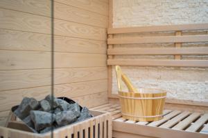 a sauna with a container of rocks and a wooden bucket at B&B Golden House & spa in Rose