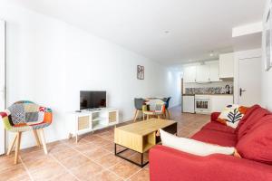 ein Wohnzimmer mit einem roten Sofa und einem Tisch in der Unterkunft Joli appartement avec jardin / Vieux-Lormont in Lormont
