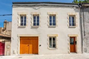 ein weißes Haus mit braunen Türen und Fenstern in der Unterkunft Joli appartement avec jardin / Vieux-Lormont in Lormont