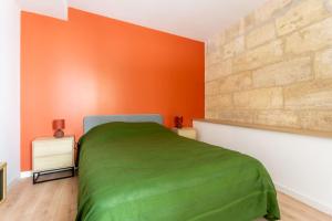 ein Schlafzimmer mit einem grünen Bett und einer orangefarbenen Wand in der Unterkunft Joli appartement avec jardin / Vieux-Lormont in Lormont