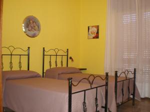 two beds in a bedroom with yellow walls at Antico Borgo in Tarsia