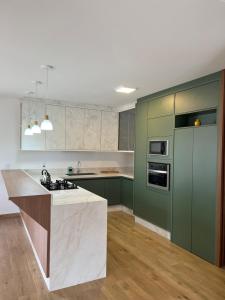 uma cozinha com armários verdes e um balcão branco em Villa Regina em Pato Branco