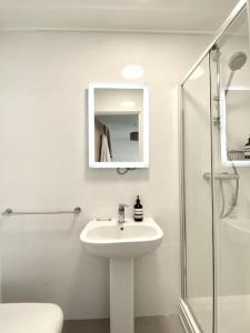 a white bathroom with a sink and a shower at Large 2bed flat near TowerBridge in London