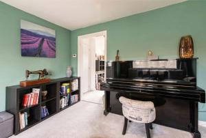 een woonkamer met een piano en een boekenplank bij Charming 2 Bed Home in Edwalton in Nottingham