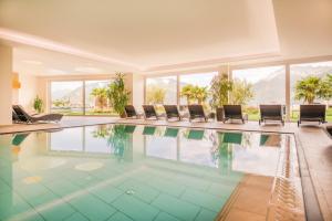 a swimming pool in a house with chairs and windows at Hotel Resmairhof in Schenna +40 photos