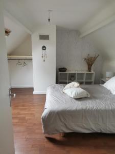 een witte slaapkamer met een groot bed en een houten vloer bij Chambre double avec salle de bains privative in Moyon