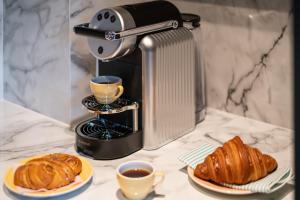 uma cafeteira com 2 chávenas de café e croissants em The Villa by Frogner House em Stavanger