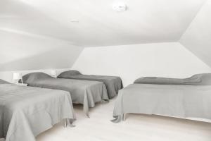 three beds in a room with white walls at Kotimaailma - Kaunis saunallinen kattohuoneisto 10lle, Espoon keskustassa in Espoo
