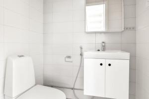 a white bathroom with a toilet and a sink at Kotimaailma - Kaunis saunallinen kattohuoneisto 10lle, Espoon keskustassa in Espoo