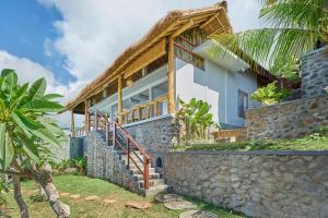 een huis aan het strand met een stenen muur bij Arungan Villas in Amed