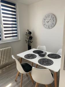 a white table with chairs and a clock on the wall at Apartmán v Třebíči in Třebíč