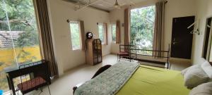 a bedroom with a green bed in a room with windows at The Sunshine Bungalow in Bangalore