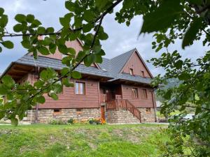 a large wooden house with a gambrel roof at Chata Dolina v Bachledke in Ždiar