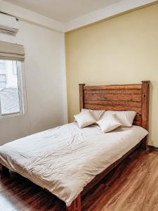 um quarto com uma cama grande e uma cabeceira em madeira em Annam The Residence - Westlake Central 2Bedrooms em Hanói