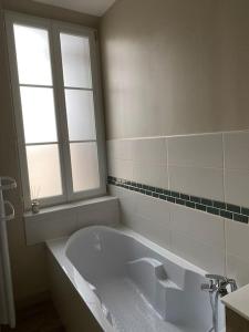 een witte badkamer met een bad en een raam bij Gîte de l’abbaye in Fécamp