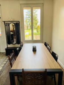 a large wooden table in a room with a large window at Maison de campagne à 2h de Paris in Droué