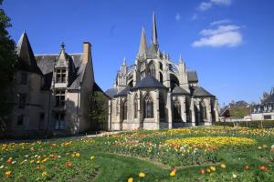 an old building with a field of flowers in front of it at Maison de campagne à 2h de Paris in Droué