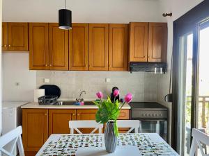 uma cozinha com uma mesa com flores cor-de-rosa num vaso em Traveller's home em Litochoro