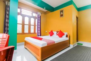 a bedroom with yellow and green walls and a bed with red pillows at Flagship Jwajalapa Homestay in Kalimpong