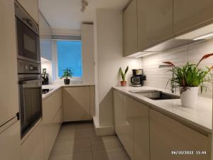 a kitchen with white cabinets and a sink and a window at The GG Spot in South Kensington Central London 2 Bedroom Apartment by Wild Boutique Apartments in London
