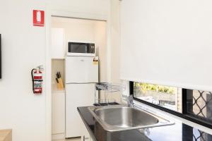a kitchen with a sink and a microwave at Great Location! Close to Restaurants & Train! in Brisbane