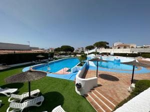 a large swimming pool with chairs and umbrellas at Residencial Macarena in Matalascañas