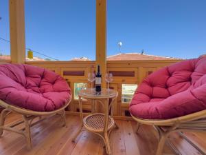 eine Veranda mit 2 Stühlen und einem Tisch mit Weingläsern in der Unterkunft Konak Ballıca - Deluxe Suite in Avanos