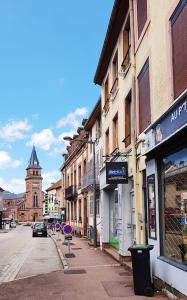 uma rua da cidade com edifícios e uma torre do relógio em Charmant studio en centre-ville em Saint-Dié-des-Vosges